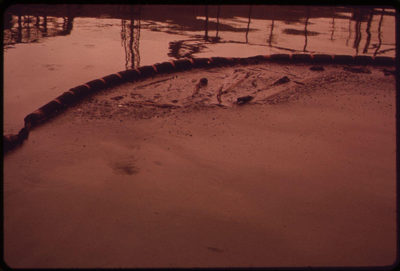 A floating containment boom holding back oil and debris on a creek